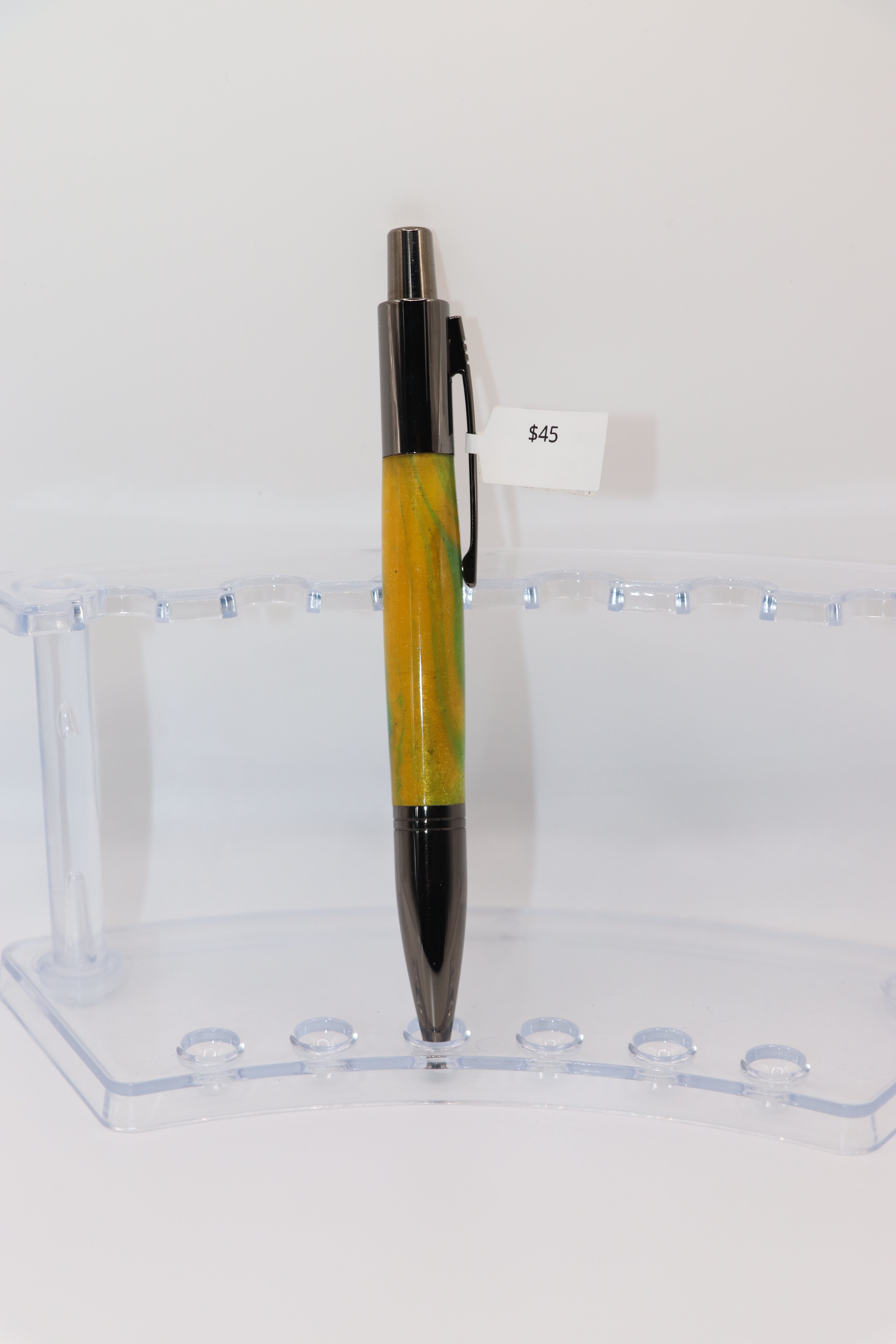 Parrot Bay Acrylic:  Pen with yellow and Gun Metal design on a clear stand against a white background